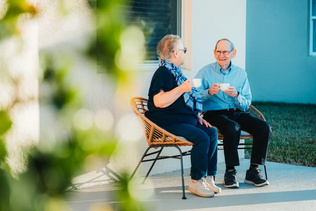 Couple sitting on a patio with mugs of coffee in hand.