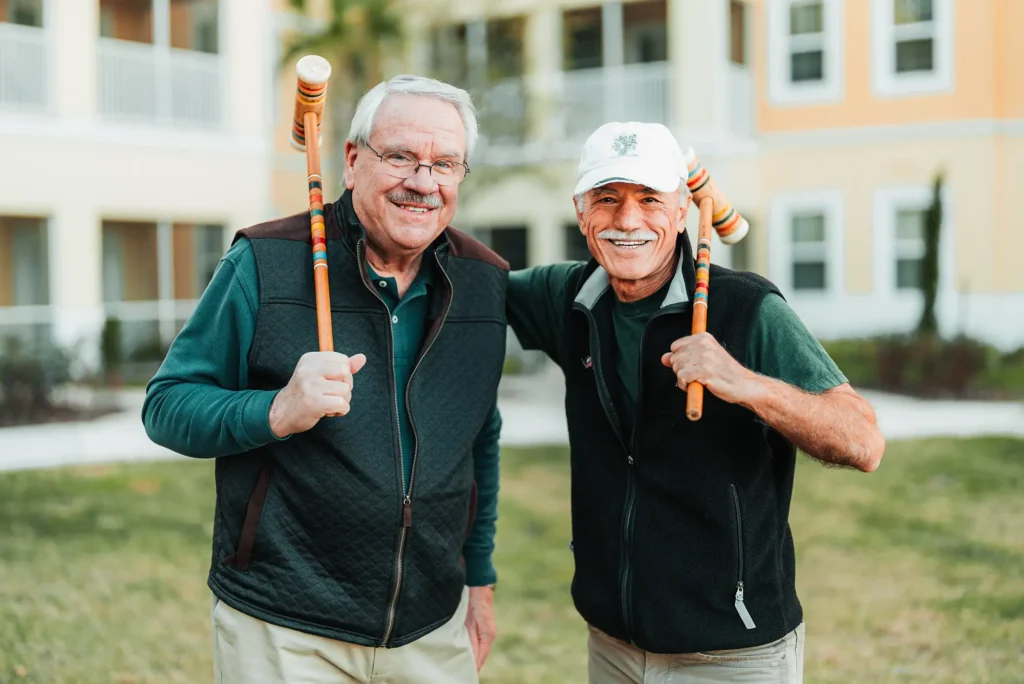 Two gentlemen with croquet mallets over their shoulders.