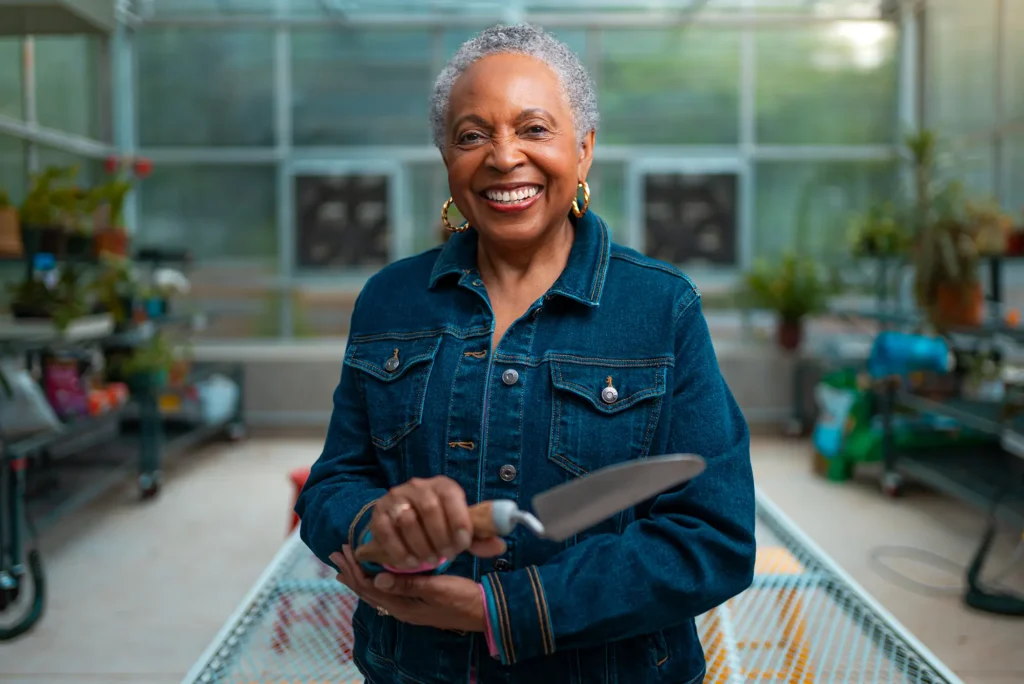 Woman holding gardening spade in greenhouse.
