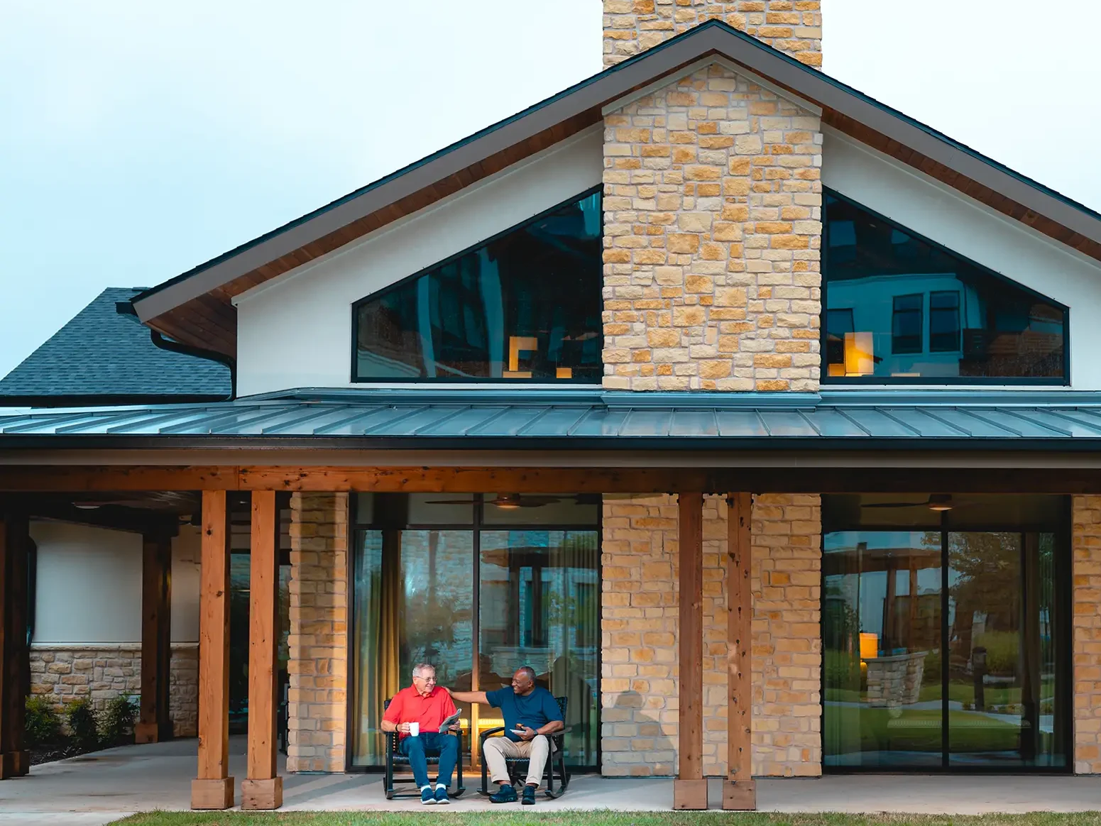 Two men sitting in rocking chairs on the patio.