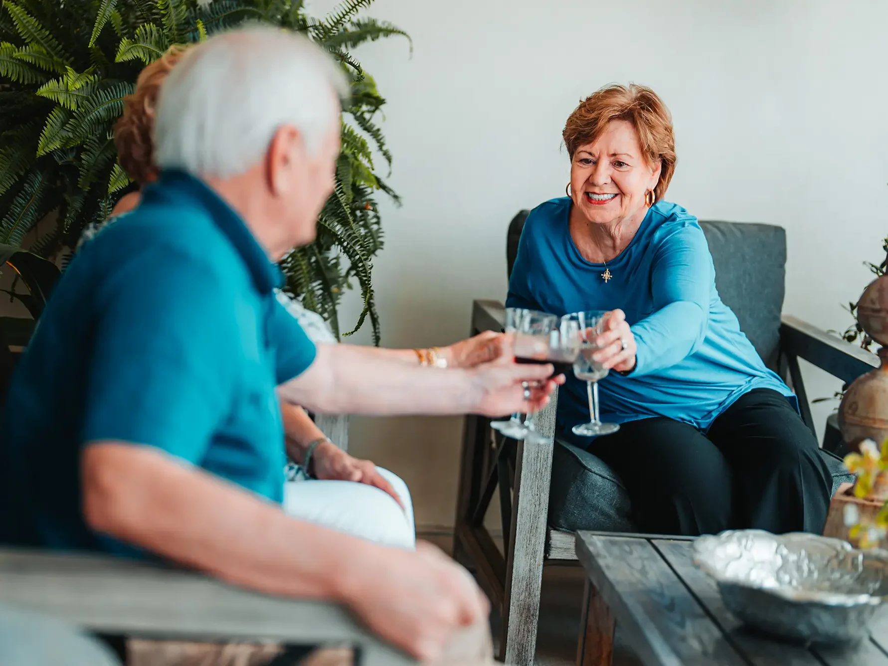3 Residents on patio "cheers-ing" glasses of wine.