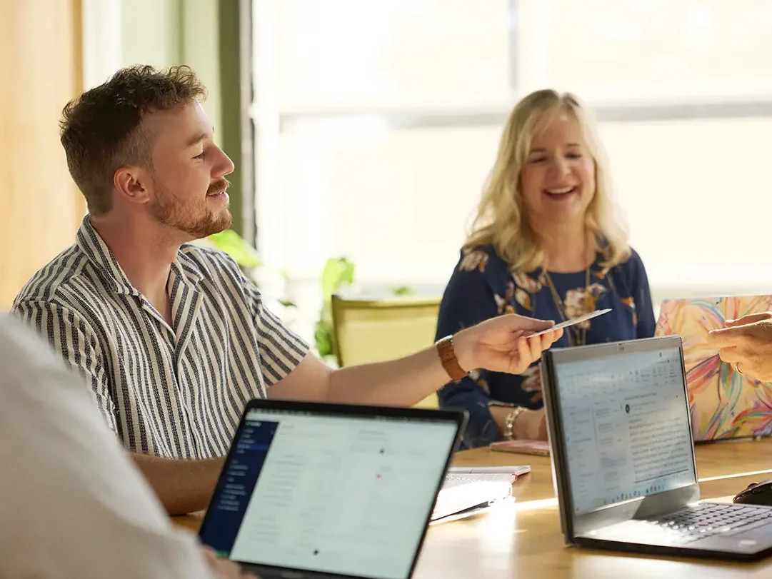 Employees having a meeting and reviewing a printed direct mail advertising piece.