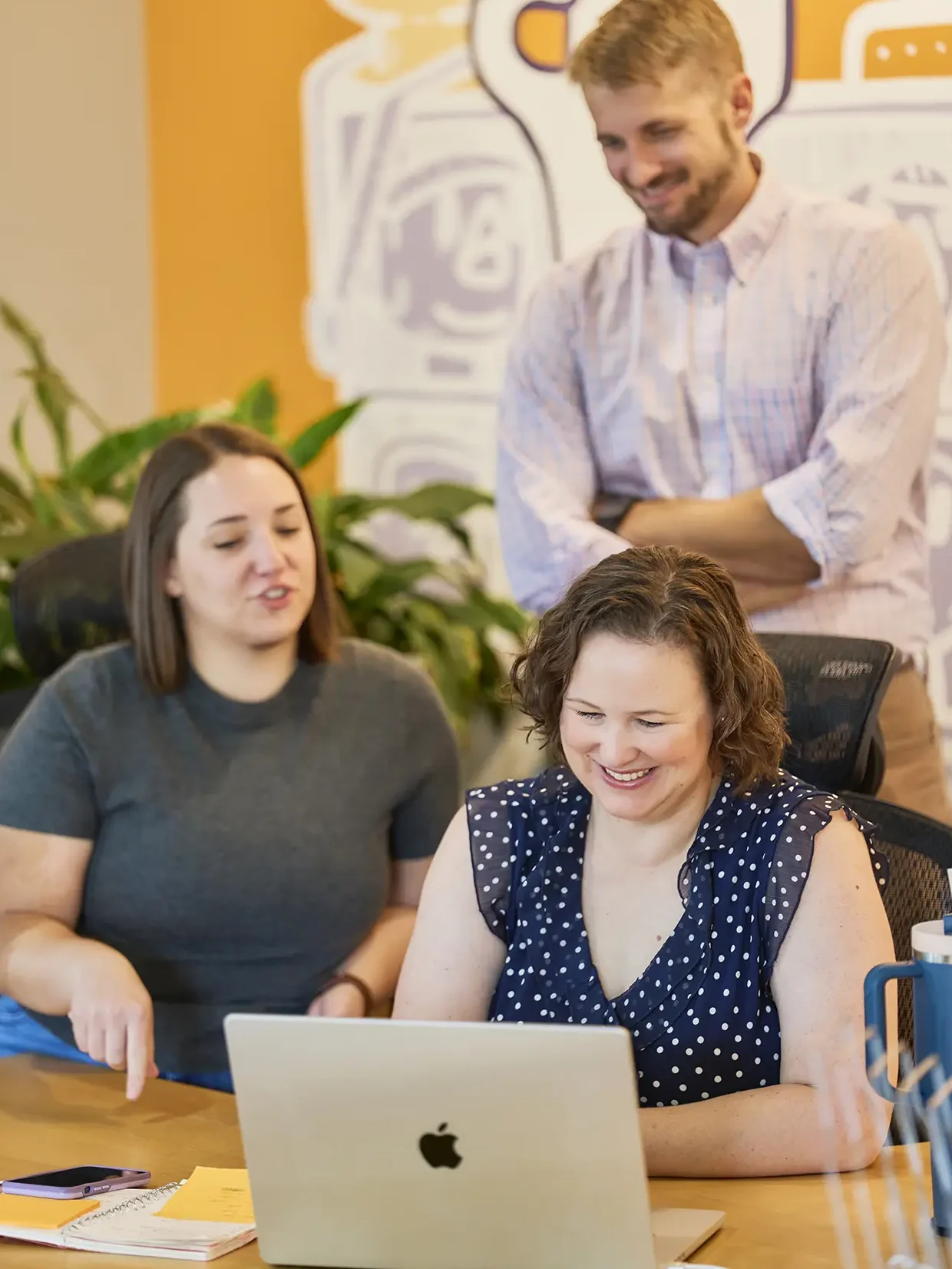 Employees gathered around a computer discussing client work.