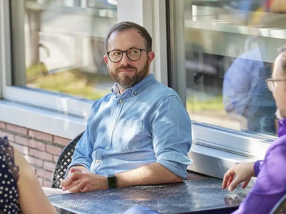 Employees sitting around an outdoor table talking.