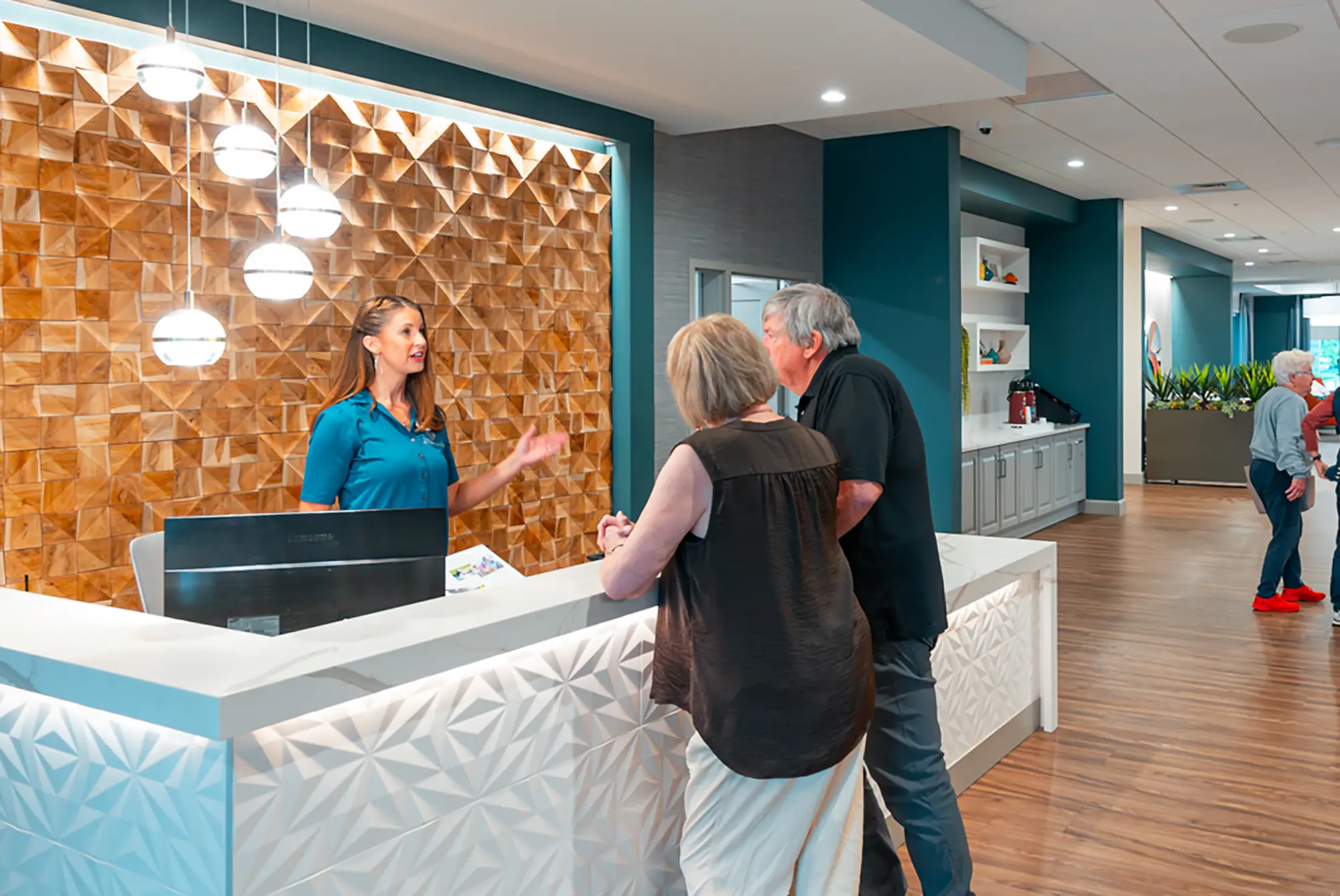 A secretary conversing with two residents at a main desk in a lobby.